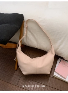 Close-up of a soft pink pebble leather hobo bag on a wooden floor with lifestyle decor
