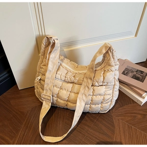 Détail du sac bandoulière matelassé beige montrant la texture et la sangle réglable