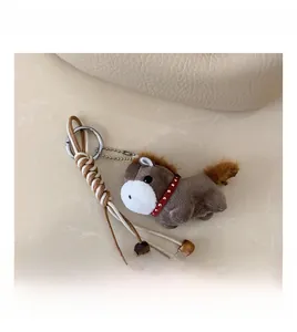 Detail of grey plush horse charm with colorful beads and woven leather strap