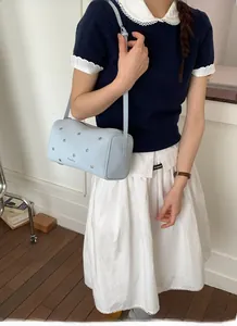 Detail of light blue cylinder bag with silver star rivets worn on shoulder