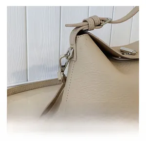 Close-up of beige lychee grain leather bag with silver metal hook and stitching detail