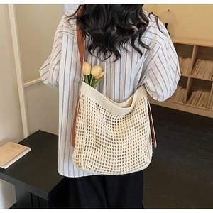 Close-up of woven tote bag with brown leather straps and hollow mesh texture detail