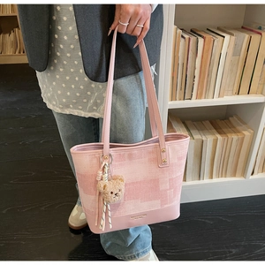 Dettaglio borsa shopper rosa con motivi geometrici, ciondolo a orso e spalline sottili