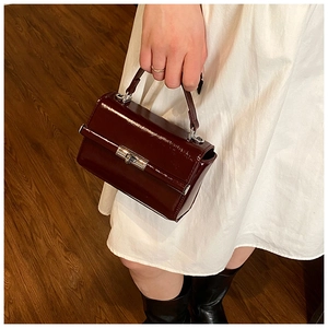 Detailed close-up of dark wine red glossy mini handbag with silver metallic twist lock
