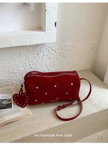 Macro detail of red cylinder bag with silver star studs and heart charm accessory