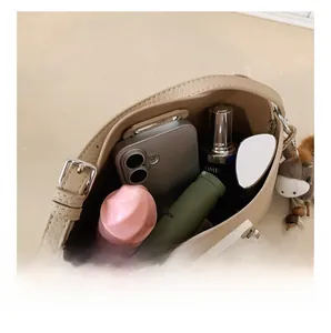 Internal capacity of beige pebble leather bucket bag showing smartphone and cosmetics