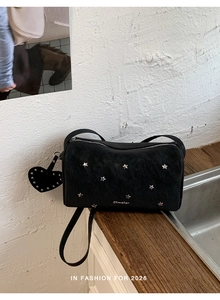 Close-up of black suede rivet bag featuring silver stars and heart-shaped pendant