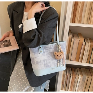 Dettaglio della borsa tote floreale azzurra con ciondolo a forma di orso in biblioteca