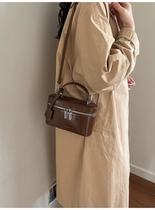 Détail d'un sac boîte en cuir marron foncé avec double fermeture éclair et poignée