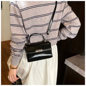 Detail of black trapezoid crossbody bag with glossy finish and silver swivel lock