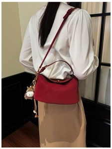 Close-up of elegant red leather shoulder bag with gold hardware and a cute horse charm