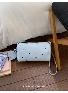 Detail of light blue pillow bag featuring metal star rivets and heart-shaped pendant detail