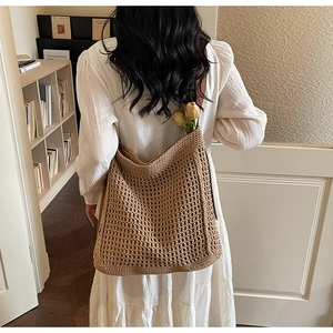 Detail of woven tote bag featuring hollow mesh texture and brown leather shoulder strap