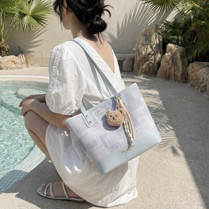Borsa tote patchwork azzurra con ciondolo a orsetto mostrata in un ambiente soleggiato