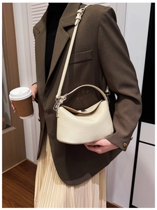 Side view of cream leather underarm bag with lychee texture on model's shoulder