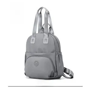 Detail view of the grey water-resistant backpack showing zippers and side pockets