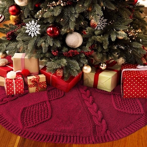 Deep red cable knit Christmas tree skirt with leaf patterns on wooden floor