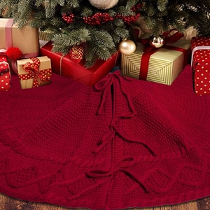 Detail of red cable knit Christmas tree skirt with decorative bow ties and warm textures