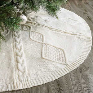 Chunky cable knit Christmas tree skirt in off-white on dark wood floor background
