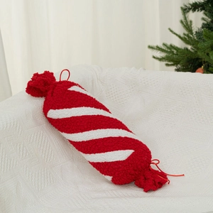 Lungo cuscino a caramella in peluche a righe bianche e rosse su un divano in stile festivo