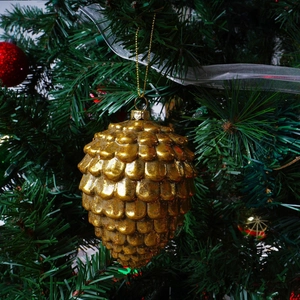 Golden pine cone Christmas ornament with textured scales hanging on a festive tree branch