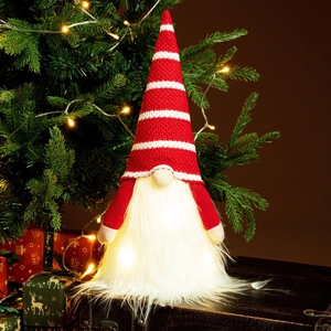 Detail of a glowing Christmas gnome with red striped hat and warm LED light in soft beard