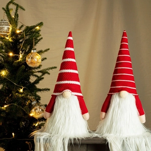 Set of two Christmas gnomes with striped knit hats and glowing lights on a holiday tree background