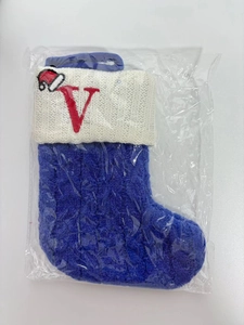 Macro shot of dark blue cable knit Christmas stocking with red letter V embroidery