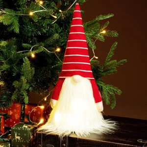 Detail of LED glowing Christmas gnome with red striped hat and warm lighted white beard
