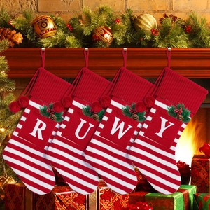 Detail of red and white striped Christmas stockings with initials hanging on a fireplace