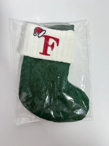 Detail of green knitted Christmas stocking with white cuff and red embroidered letter F