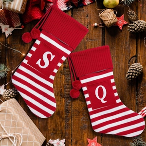 Red and white striped Christmas stockings with personalized letters on vintage wood