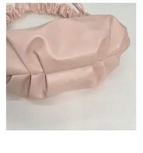 Detailed view of pink pleated cloud bag texture and glossy leather finish material