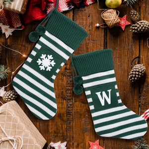 Close-up of green striped knitted Christmas socks with snowflake and letter W patterns