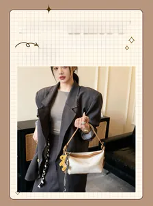 Détail du sac à bandoulière en cuir blanc avec garniture brune et charm chien
