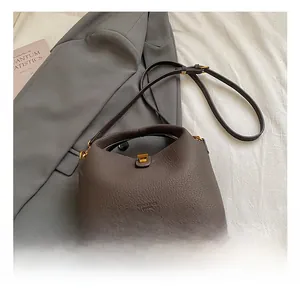 Detailed view of coffee leather bucket bag with gold hardware on blazer background