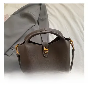 Detail of brown lychee grain leather bucket bag featuring elegant gold metal twist lock hardware