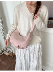 Detail of pink pleated hobo bag featuring a knotted wide shoulder strap and soft texture