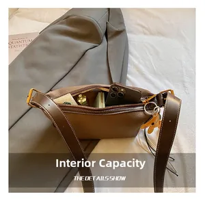 Capacité interne du sac bandoulière en cuir marron avec objets du quotidien