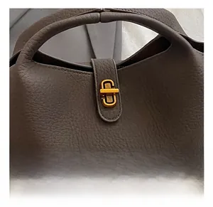 Detailed close-up of dark brown lychee grain leather and golden metal twist-lock buckle