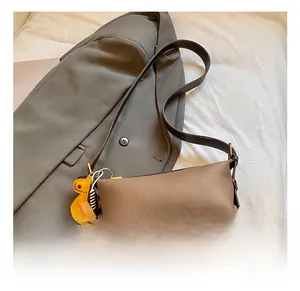 Vue détaillée du sac bandoulière marron motif litchi avec logo doré et charme d'ours