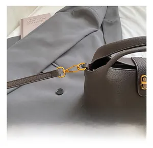 Detail of premium gold hardware hook on a vintage textured leather bucket handbag
