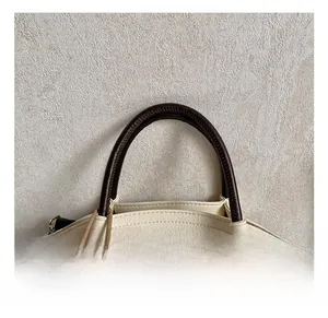 Detailed macro view of cream leather tote bag with brown handles and plush bear charm