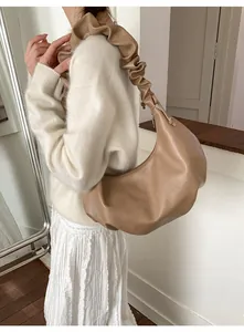 Detail of camel crescent shoulder bag with pleated handle and minimalist leather design