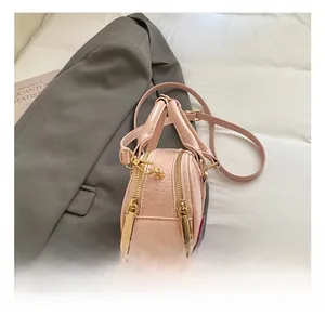 Close-up of pink textured leather handbag with shiny gold zippers and metal hooks