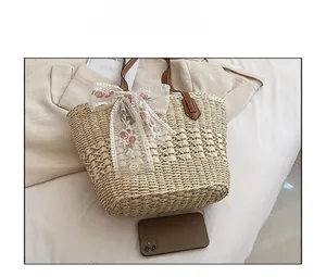 Detail of straw tote bag featuring white lace bow with pink rose embroidery and pearls