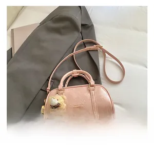 Detail of pink PU Boston bag with textured finish, logo print and plush bear charm
