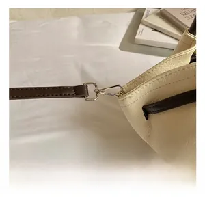 Detail of silver lobster clasp and leather strap on a cream pebbled tote bag