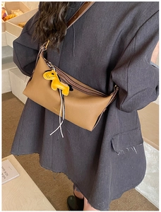 Détail de sac bandoulière en cuir marron avec breloque cheval jaune et franges