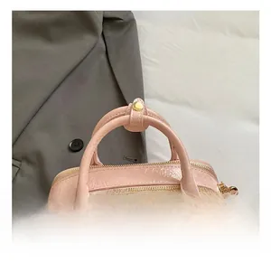 Detailed shot of pink pleated leather handbag with dual zippers and gold hardware